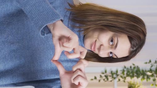 Woman Makes Heart Shape with Hands Indoors