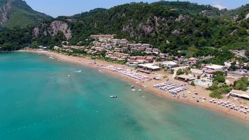 Vue aérienne par drone de la plage bondée de Glyfada à Corfou avec des rangées de parasols, de chaises longues,