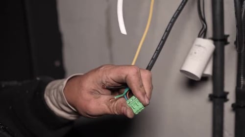 Hands Connecting Wires to a Terminal Block