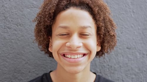 Smiling Teen with Curly Hair against Gray Background