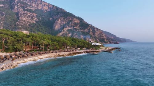 Tranquil Blue Water Gently Washes the Rocky Shore Lined with Beach Umbrellas and Charming Cabins