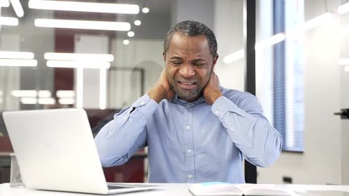 Mature Man Experiencing Neck Pain at Office Desk