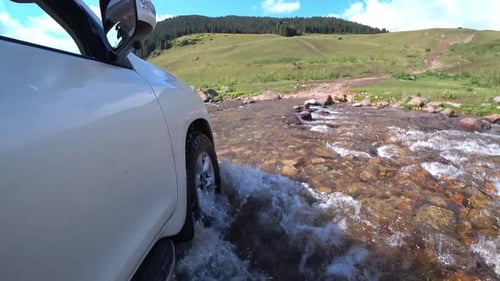 Ein weißer SUV fährt durch Fluss und Schlamm