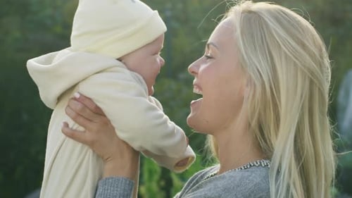 Mother Kisses Her Baby while Lying on the Grass.
