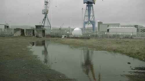 Blick von der Pfützenspiegelung zu großen Kränen