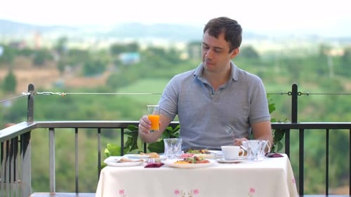 Man Enjoying Breakfast on Outdoor Patio with Scenic Countryside View