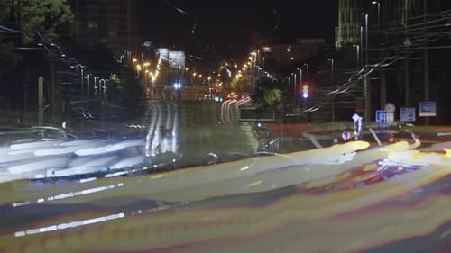 A long-exposure shot of a city street at night, filled with bright, colorful light trails and glowin