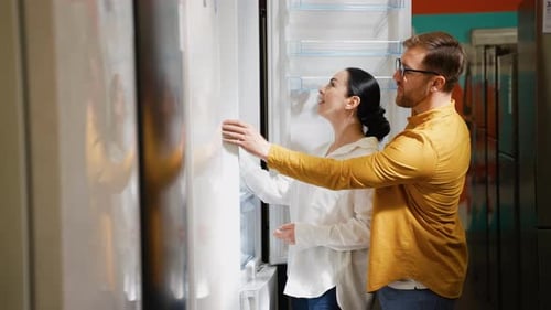 Young Couple is Viewing Fridge in Home Appliances Store