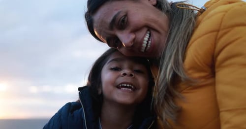 Glückliche lateinamerikanische Mutter und Tochter lächeln vor der Kamera mit Sunset in The