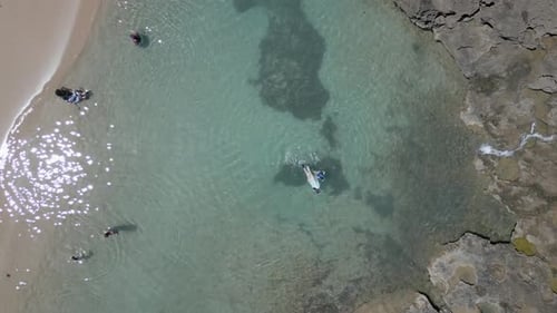 Drone shot straight down looking at people snorkeling and having fun in the ocean water at a beautif