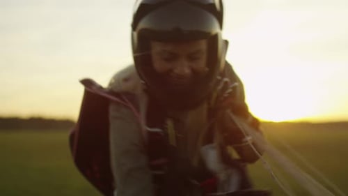 Girl Skydiver in Helmet is Picking Up Parachute after Successful Landing