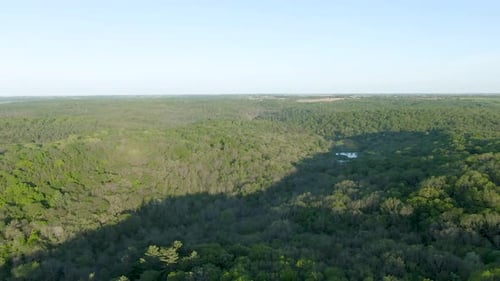 Aerial over Wisconsin hills covered in thick foliage during sun set. Mountains cast shadows over hil