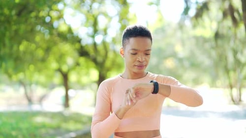 Sport african american woman looking smart watch at modern track. runner using smartwatch fitness