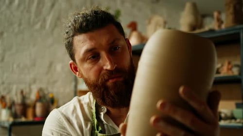Adult Man Inspects Clay Vase in Studio
