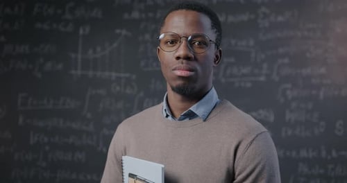 Portrait of Confident African American Man College Professor Holding Books Standing in Classroom