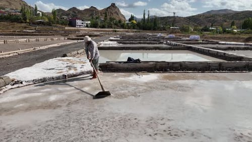Aerial View Of Worker Working In Salt Ponds