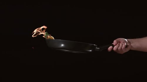 Vegetables on Fire in Frying Pan Held by Hand