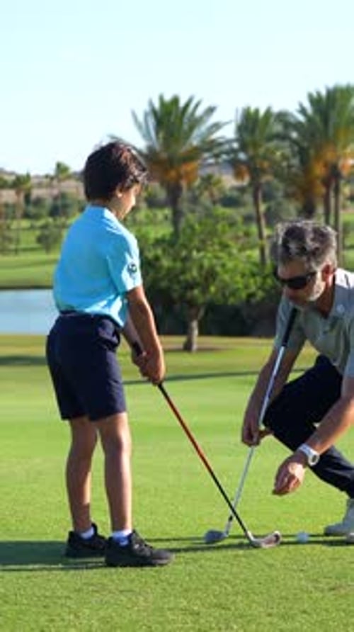 Boy Learns Golf Swing on Green Golf Course