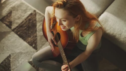 Woman Plays Guitar with Laptop at Home