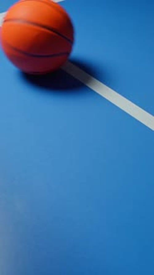 Basketball Rolling and Bouncing Across Blue Court Surface