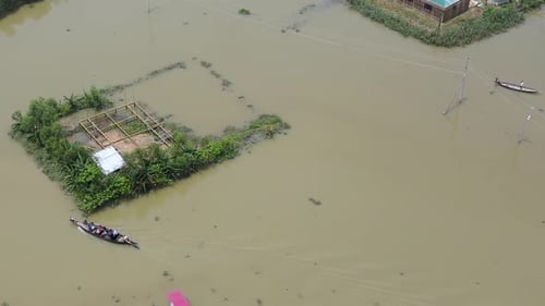 Aerial view over boat transporting people in flood affected submerged village homes in Bangladesh