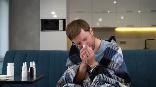 A Man with a Strong Runny Nose Sneezes on the Couch