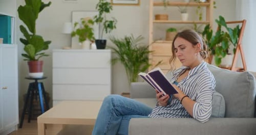 Woman Reading a Book on Sofa at Home