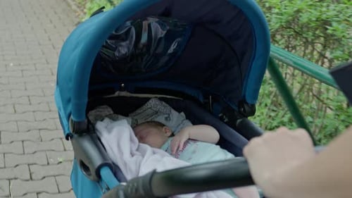 Infant Baby in Stroller with Mother Pushing While Walking in the Park