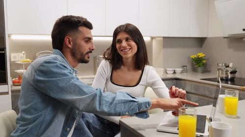 Young Couple Using Laptop in Modern Kitchen