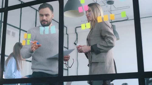 Bunch of stickers on the glass. Professional workers are in the modern office together.