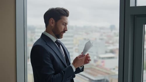 Pensive Executive Manager Holding Paper Airplane Standing At Office Window Looking Cityscape Clos...