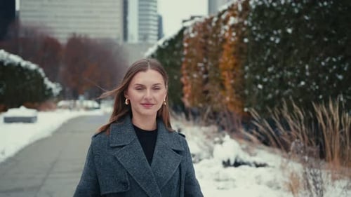Woman Walks Toward Camera in Snowy Urban Park