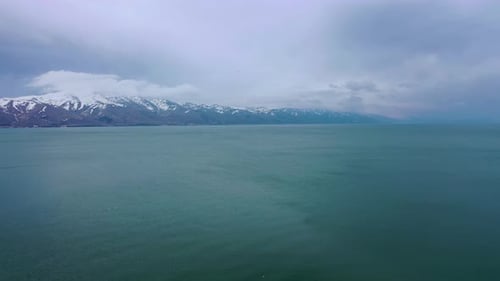 Luftdrohne über Meerwasser mit schneebedeckten Bergen