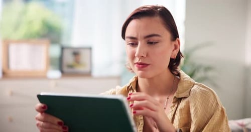 Woman Smiles While Looking at Tablet at Home