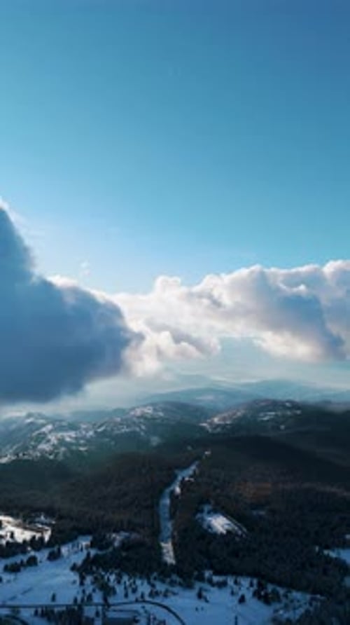 Horizon de montagne aérien à haute altitude sous un ciel bleu vif et des nuages