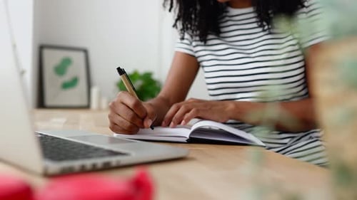 Close Up View of Young Student Woman Taking Notes While Using Laptop at Home