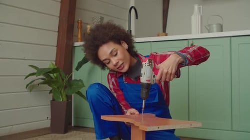 Black Female Repairing Furniture and Unscrewing Screws with Cordless Screwdriver