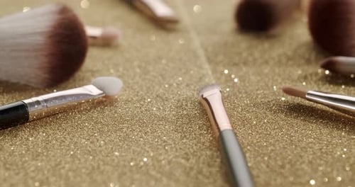 Professional Cosmetic Makeup Brushes Set Rotating on a Gold Glittering Background