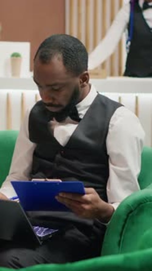 Man Working on Laptop and Taking Notes in Office