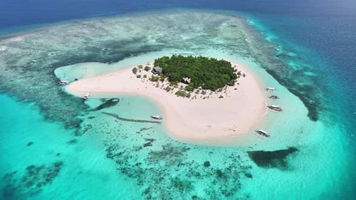 Aerial drone approaches pristine Patawan Island surrounded by turquoise shallows in Balabac, Palawan