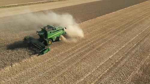 Drone Shot of Green John Deere Combine Harvester Harvesting with Dust on Sunny Day UK