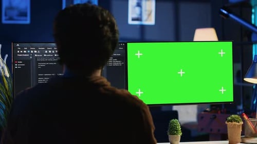 Programmer Typing Complex Code on Green Screen Computer in Neon Lit Home Office