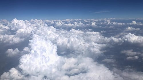 Aerial view of fluffy cumulus clouds from airplane altitude with blue skies
