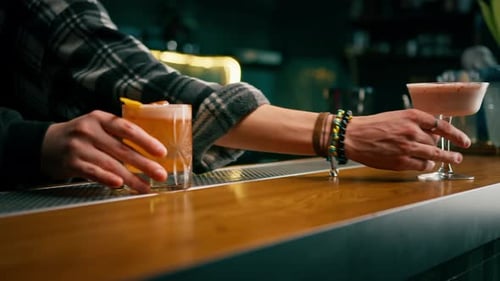Close-up of guests of the bar holding ready-made delicious alcoholic cocktails in their hands