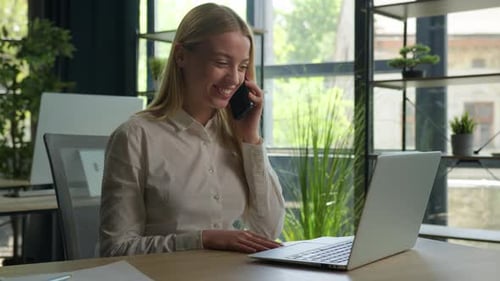 Woman Talking on Phone and Working at Laptop