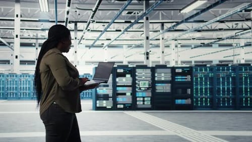 Data Center Worker Using Laptop to Manage Software Updates for System Stability