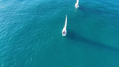 A small sailboat is navigating through the vast open ocean, surrounded by nothing but water. The sai