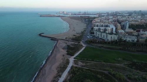 Side aerial view of a beachfront city buildings with the seaport in the background