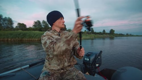 Mann fischt vom Boot aus. Junger Amateurangler fischt bei Sonnenuntergang vom Boot
aus