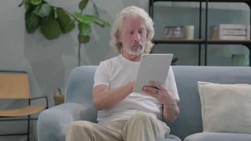 Senior Man Using Tablet Device on Couch at Home